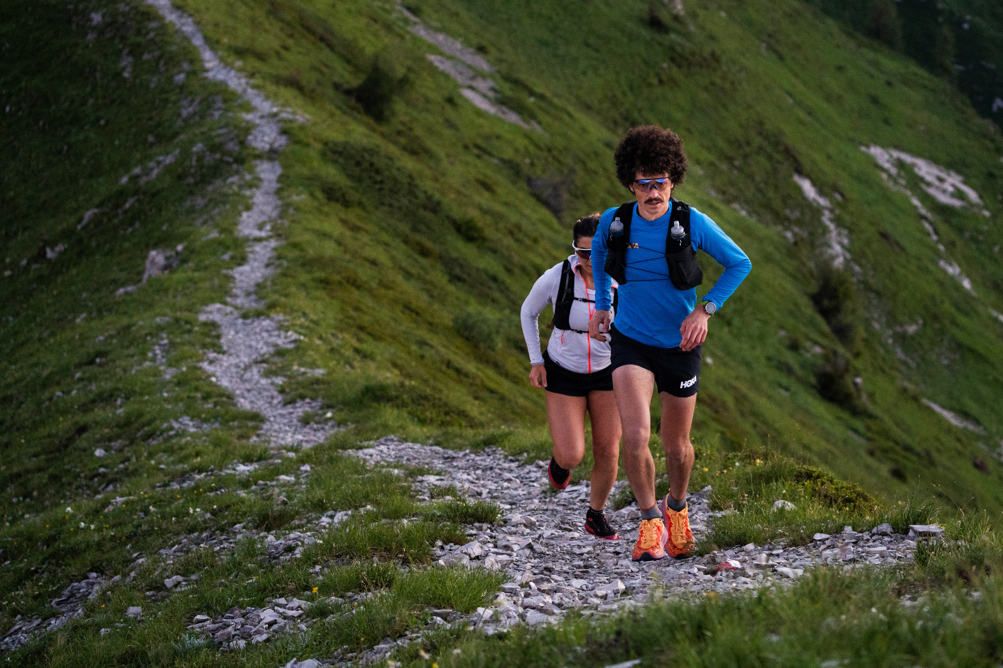 Two runners on a mountain trail during sunset